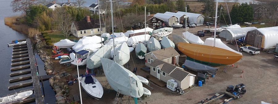 Aerial view of Frank Hall Boat Yard during winter layup, with shrink-wrapped boats and the waterfront docks on the Pawcatuck River